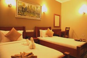 达累斯萨拉姆切尔西酒店的酒店客房设有两张床,墙上挂着一张照片。