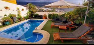伊科德洛斯维诺斯Pintadera house Caracola的游泳池旁配有椅子和遮阳伞