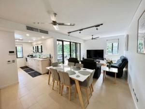 达尔文Luxury Waterfront Apartment (2 bedrooms)的厨房以及带桌椅的起居室。