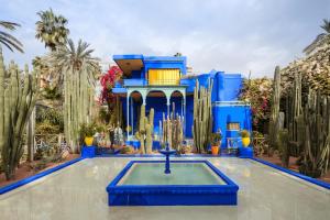 马拉喀什Riad HAFSSA & Spa的一座蓝色的建筑,在一座带仙人掌的院子中设有喷泉