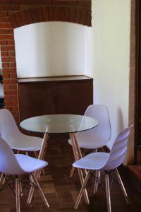 UmtaliLovely 4 bed in Mutare - 2178的四周摆放着四把白色椅子的玻璃桌
