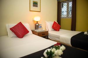 关丹Sweet Inn Guest House的配有红色和白色枕头的客房内的两张床
