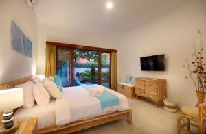 沙努尔Villa Lotus Flower Sanur的一间卧室配有一张大床和电视