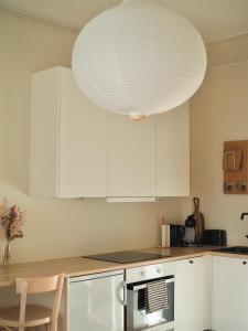赫尔辛基Beautiful design studio in the heart of Kallio的厨房配有白色橱柜和大型灯具