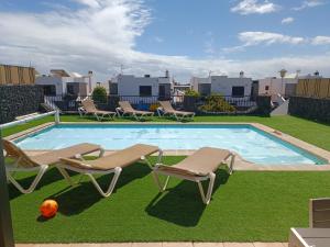 蒂亚斯Villa Juanita, Puerto del Carmen, Lanzarote的一个带2把躺椅和球的游泳池