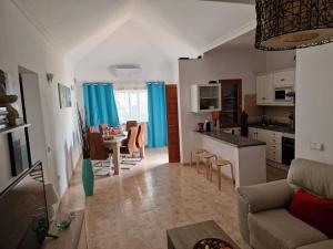 蒂亚斯Villa Juanita, Puerto del Carmen, Lanzarote的带沙发的客厅以及带蓝色窗帘的厨房