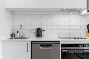 奥克兰Contemporary Urban Retreat的白色的厨房设有水槽和炉灶。