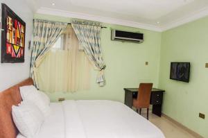 拉各斯BEN AUTO Hotel的卧室配有白色的床、窗户和书桌