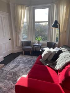 拉格斯Beautiful traditional flat in the center of Largs.的客厅里的一个红色沙发,带有窗户