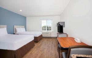 迈尔斯堡Extended Stay America Select Suites - Fort Myers - Northeast的酒店客房设有两张床、一张桌子和一张桌子。