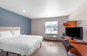 贝瑟默Extended Stay America Select Suites - Birmingham - Bessemer的一间卧室配有一张床和一台平面电视