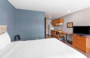 贝瑟默Extended Stay America Select Suites - Birmingham - Bessemer的一间卧室配有一张床和一张书桌及电视