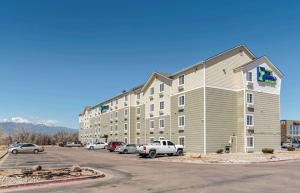科罗拉多斯普林斯Extended Stay America Select Suites - Colorado Springs - Airport的大型公寓大楼,停车场有车辆停放