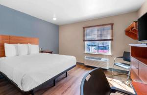 杰克逊维尔Extended Stay America Select Suites - Jacksonville - North的一间卧室配有一张床、一张书桌和一个窗户。