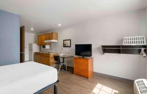 莱克兰Extended Stay America Select Suites - Lakeland的一间卧室配有一张床和一张书桌及电视