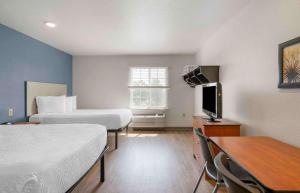 莱克兰Extended Stay America Select Suites - Lakeland的酒店客房设有两张床、一张桌子和一台电视。