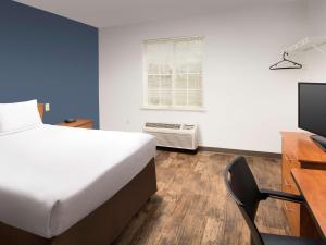 拉斯克鲁塞斯Extended Stay America Select Suites - Las Cruces的一间卧室配有一张床、一张书桌和一台电视