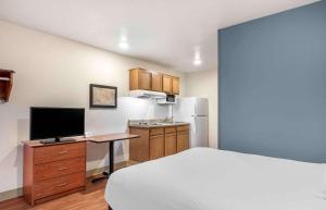 Extended Stay America Select Suites - Louisville - South的一间卧室配有一张床和一张书桌及电视