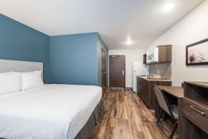 Mendota HeightsExtended Stay America Suites - Minneapolis - Airport - Mendota Heights的酒店客房配有一张床、一张书桌和一间厨房。