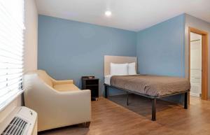 彭萨科拉Extended Stay America Select Suites - Pensacola - Northeast的一间卧室配有一张床和一把椅子