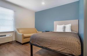 彭萨科拉Extended Stay America Select Suites - Pensacola - Northeast的一间卧室配有一张床和一把椅子