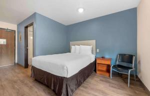 奥兰多Extended Stay America Select Suites - Orlando - East的一间卧室配有一张床、一张桌子和一把椅子