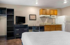 奥兰多Extended Stay America Select Suites - Orlando - South的一间带床和冰箱的小厨房