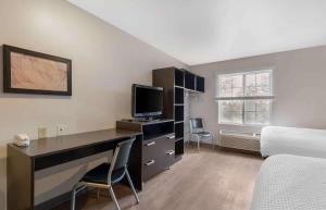 奥兰多Extended Stay America Select Suites - Orlando - South的一间卧室配有一张桌子、一台电脑和一张床