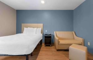 奥兰多Extended Stay America Select Suites - Orlando - South的一间卧室配有一张大床和一把椅子