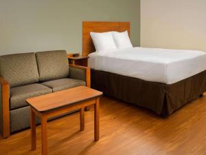 莱赫Extended Stay America Select Suites - Provo - American Fork的一间卧室配有一张床和一张沙发,旁边是椅子