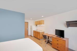 斯普林代尔Extended Stay America Select Suites - Springdale的客房设有一张桌子、一台电视和一间厨房