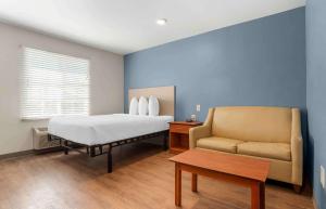 塔拉哈西Extended Stay America Select Suites - Tallahassee - Northwest的一间卧室配有一张床和一张沙发