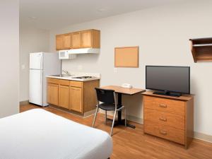 普兰菲尔德Extended Stay America Select Suites - Indianapolis - Plainfield的客房设有一张桌子、一台电视和一间厨房