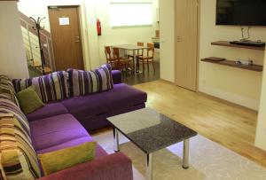 派尔努Embrace Hotel & Apartments的客厅配有紫色沙发和桌子