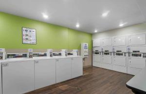 坦帕Extended Stay America Suites - Tampa - Northeast的洗衣房配有白色的机器和绿色的墙壁