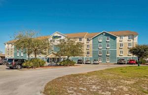 沃尔顿堡滩Extended Stay America Select Suites - Fort Walton Beach的停车场内停放汽车的大型建筑