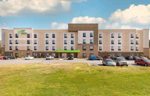 格林维尔Extended Stay America Premier Suites - Greenville - Woodruff Road的停车场内停放汽车的大型建筑