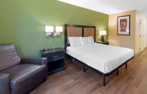威克斯巴勒Extended Stay America Select Suites - Wilkes - Barre - Scranton的卧室里的床和沙发,卧室里配有一张床和椅子