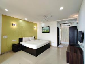 达曼Golden Chariot Hotel Daman的一间卧室配有一张床和一台电视