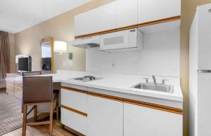 奥兰多Extended Stay America Select Suites - Orlando - Southpark - Equity Row的厨房配有白色橱柜、水槽和椅子