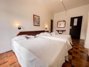 弗洛里亚诺波利斯Canas Gold Praia Hotel的客房内的两张床和白色床单