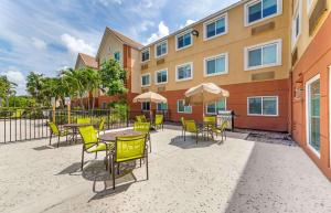 迈阿密Extended Stay America Premier Suites - Miami - Airport - Miami Springs的一座配有桌椅的庭院和一座建筑