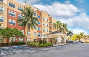 迈阿密Extended Stay America Premier Suites - Miami - Airport - Doral - 25th Street的停车场前有棕榈树的建筑