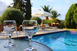 罗希姆诺Olive Villa Crete的两个酒杯坐在桌旁的游泳池旁