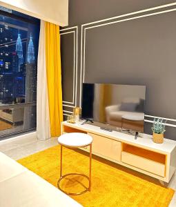 吉隆坡Axon Residence Bukit Bintang By TR Suites的客厅配有电视、椅子和桌子