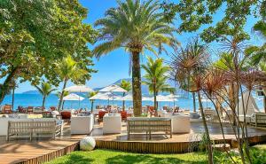 伊利亚贝拉DPNY Beach Hotel & SPA Ilhabela的一个带椅子和棕榈树的海滩的度假酒店