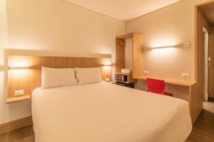 阿雷格里港Hotel Moov Porto Alegre的卧室配有白色的床和红色椅子
