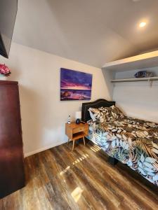 亨廷顿海滩Surf city House的一间卧室配有一张床,铺有木地板
