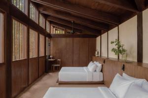 巴卡拉尔Boca de Agua Bacalar的一间卧室设有两张床、木墙和窗户。