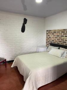 莫尼基拉DinoAgro Potrero Grande的卧室配有白色的砖墙床